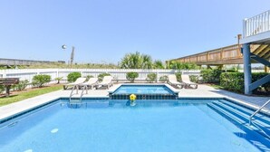 Una piscina rectangular con borde de azulejos, rodeada de sillas de descanso y una terraza de madera.