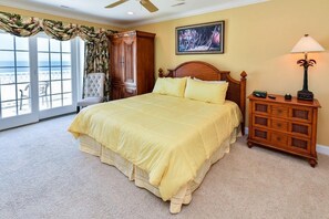 A bedroom with a large bed, a wooden nightstand, a chair, a dresser, and a window with curtains. - Oceanfront 6 BR with a Private Pool! Southern Belle (Garden City)