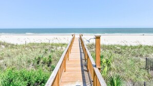 Un muelle de madera que conduce a una playa, con vista despejada al océano.