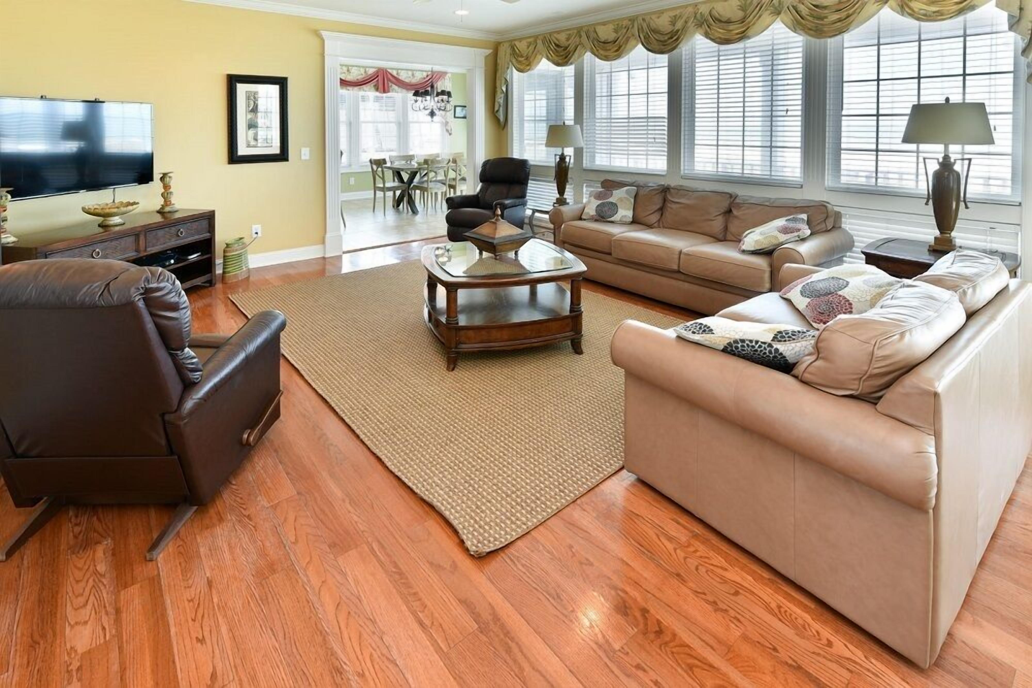 Una sala de estar con un sofá de cuero marrón, un sofá color beige, una mesa de centro y un televisor.