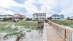 Una pasarela de madera que lleva a una hilera de casas de playa con varios pisos y balcones.