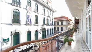 A balcony with a railing, potted plants, and a building with green shutters and a sign for 'MUSEE CANAL'.