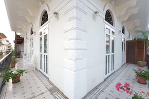 Um edifício branco com janelas em arco e varanda com telhas.