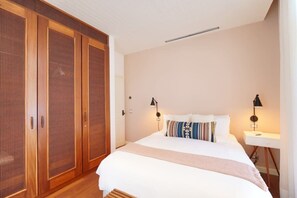 Un dormitorio con una cama grande, dos lámparas de noche, un armario de madera y una mesita de noche.