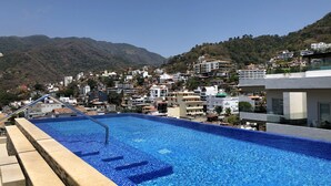 Ein Swimmingpool mit Blick auf eine Stadt am Hang.