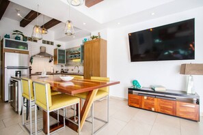 Una cocina moderna con una mesa de comedor de madera, sillas amarillas y un televisor negro montado en la pared.