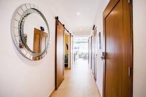 Un pasillo con un espejo grande, puertas de madera y vista a un salón.