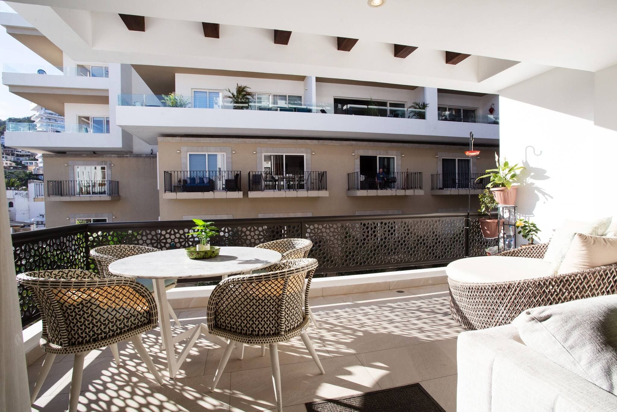 Ein Balkon mit Gartenmöbeln, einem Tisch und Topfpflanzen.