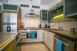A modern kitchen with stainless steel appliances, a central island, and a variety of storage cabinets.