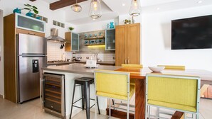 Eine moderne Küche mit Edelstahlgeräten, Holzschränken und einer zentralen Kochinsel mit Barhocker.