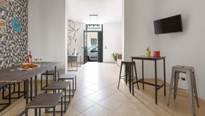 A modern dining area with a long table, multiple chairs, and a TV mounted on the wall. - 2982 Porta Barocca by Barbarhouse (Lecce)