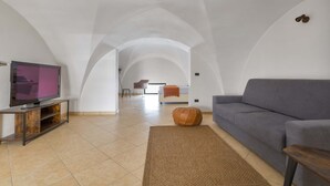 A spacious living area with a grey sofa, a television on a wooden stand, and a large window in the background. - 2982 Porta Barocca by Barbarhouse (Lecce)