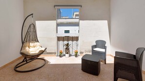A balcony with a hanging chair, two potted plants, and wicker furniture. - 2982 Porta Barocca by Barbarhouse (Lecce)