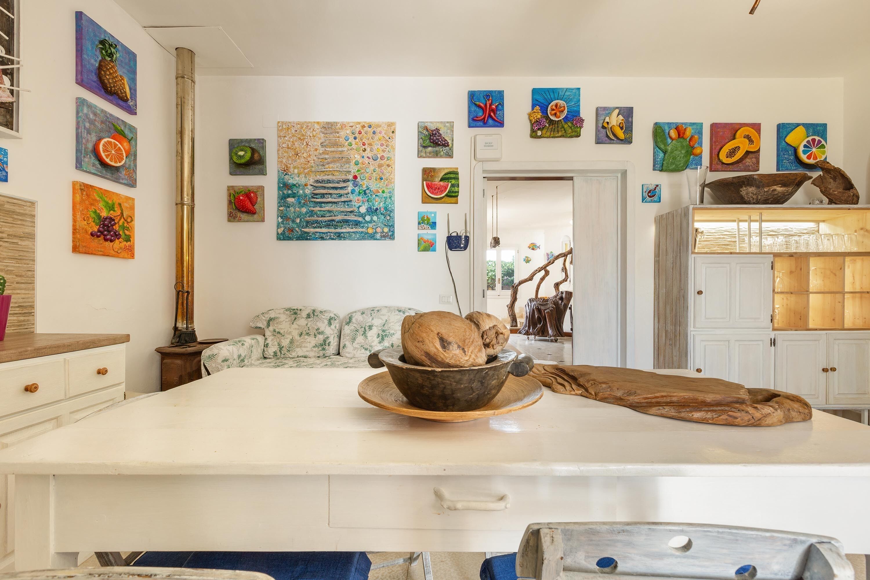 A kitchen with a central island, a dining area with a sofa, and various wall art.
