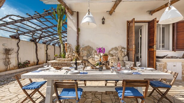 An outdoor dining area with a table set for six, surrounded by wooden chairs with blue cushions. - 2260 Residenza Artistica - Villa Armida by Barbarhouse (Lecce)