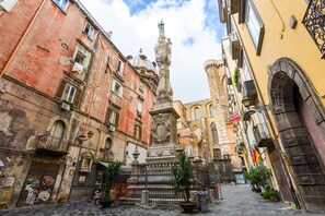 A historic street with a fountain, cobblestone pavement, and traditional architecture. - Tribunali 194 - Cozy Flat in Center (Naples)