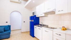 A compact kitchen with white cabinets, a blue refrigerator, and a built-in microwave. - Tribunali 194 - Cozy Flat in Center (Naples)