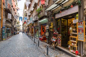 A cobblestone street lined with shops, including a jewelry store with a display of trinkets and a sign for 'La Bottega'. - Tribunali 194 - Cozy Flat in Center (Naples)