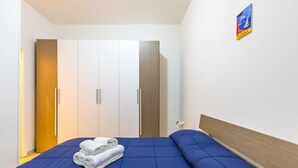 A hotel room with a bed, a wardrobe, and a poster on the wall. - Tribunali 194 - Cozy Flat in Center (Naples)