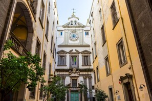 A narrow street with a church featuring a prominent clock and a green door. - Tribunali 194 - Cozy Flat in Center (Naples)