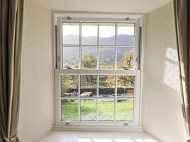 Una habitación con un amplio ventanal que da a un paisaje verde con árboles y una cadena montañosa distante.