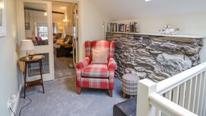 Un salón acogedor con un sillón de cuadros, una chimenea de piedra y un tragaluz arriba.