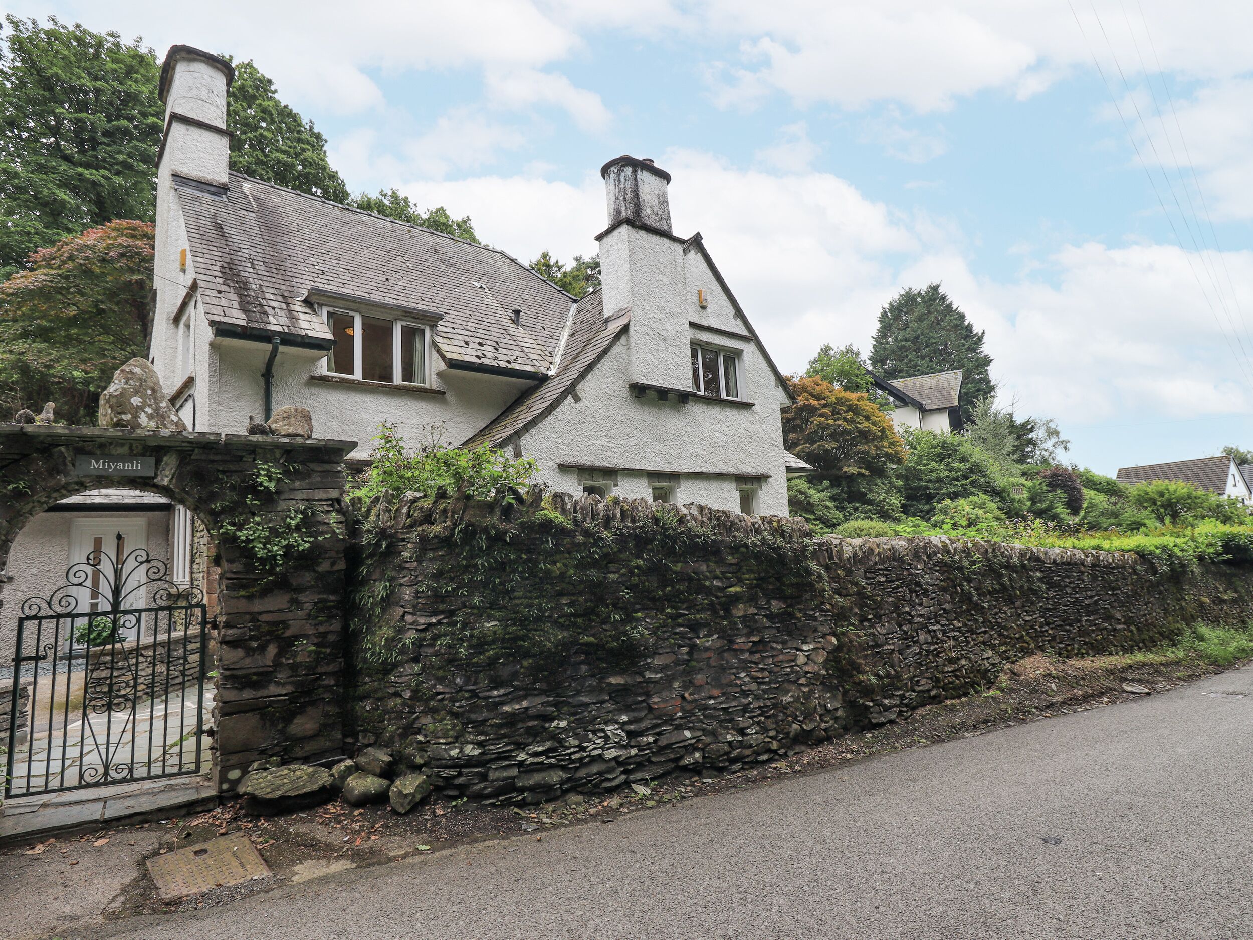 A traditional stone-walled house with a tiled roof, a stone gate, and a clear sky.