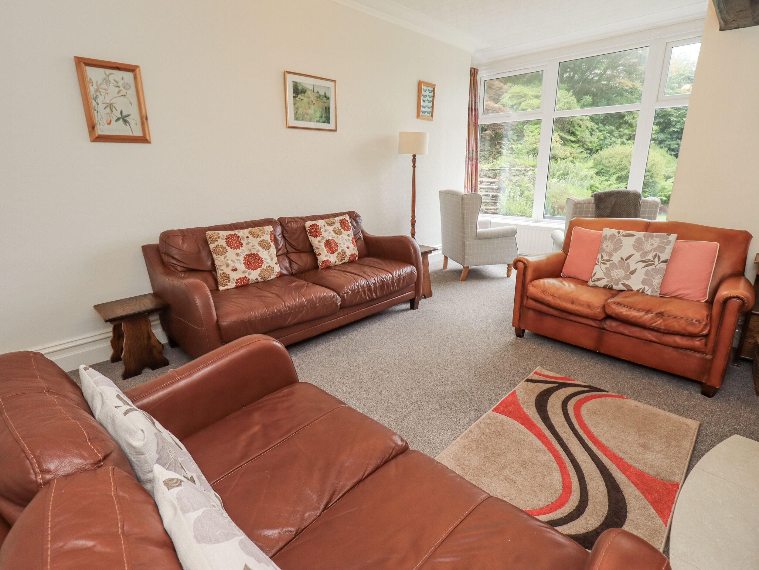 A living room with two brown leather sofas, a grey armchair, and a patterned rug.