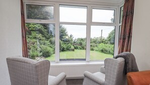 A room with two armchairs facing a large window overlooking a garden. - Miyanli (Windermere)