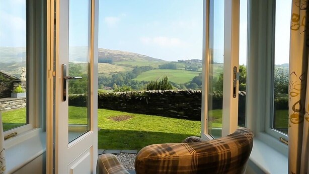 A room with a view of rolling hills and a stone wall. - Thyme Out (Windermere)