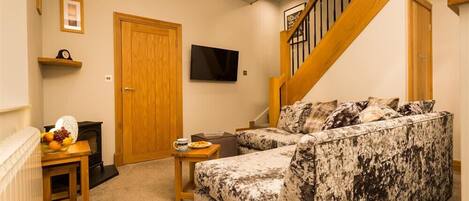 A living room with a sofa, a coffee table, a TV, a wooden door, and a staircase.