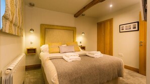 A bedroom with a large bed, two bedside tables, a wooden wardrobe, and a radiator. - Thyme Out (Windermere)