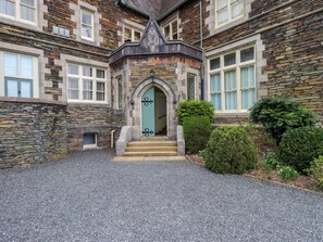 Un bâtiment en pierre doté d’une entrée accueillante, d’un petit jardin et d’une allée gravillonnée.