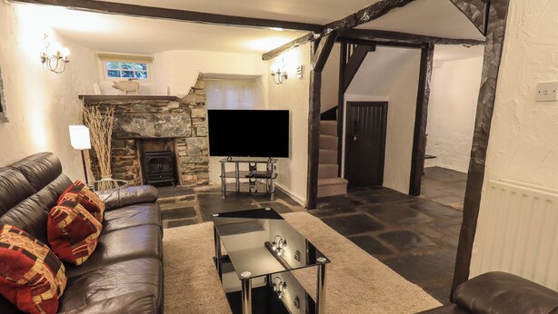 Ein gemütliches Wohnzimmer mit Kamin aus Stein, einer Ledersofa und einem Flachbildfernseher.