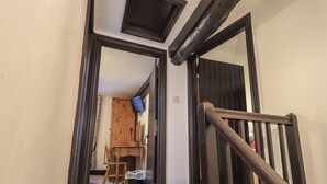 Ein Flur mit einer Holztür, einem kleinen Tisch mit Stuhl, einem an der Wand befestigten Fernseher und einer Treppe mit Handlauf.