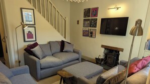 Ein Wohnzimmer mit einer Sofagarnitur, einem Kamin, einem Fernseher und gerahmten Bildern an der Wand.