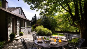 A stone building with a garden patio. - Underheron (Ambleside)