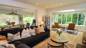 A modern living room with a black sofa, a round coffee table, and a dining area with a wooden table and chairs. - Underheron (Ambleside)