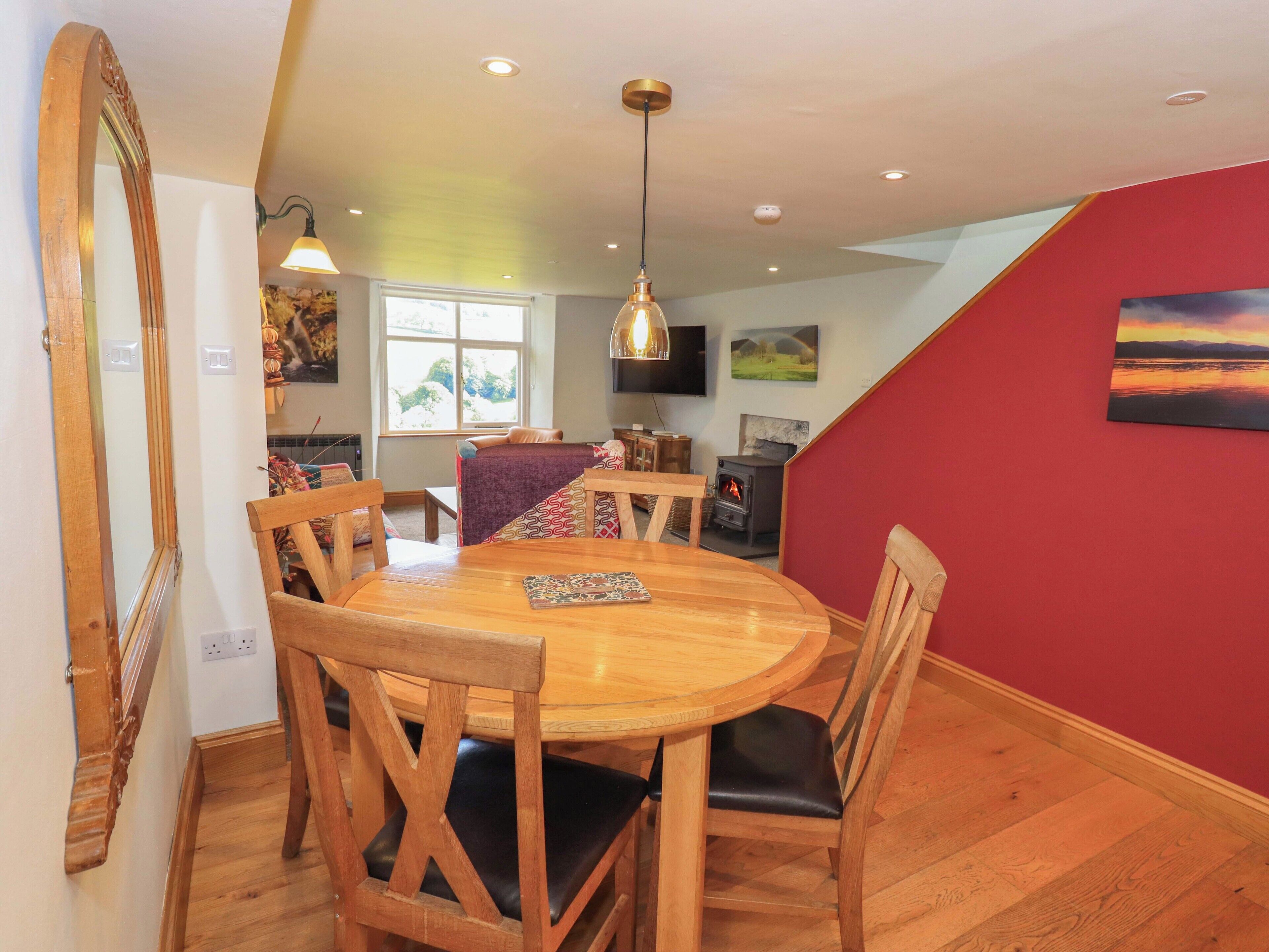 Un comedor acogedor con una mesa y sillas de madera, una pared de acento roja y una chimenea.
