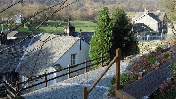 Un village rural avec des maisons en pierre, un escalier en bois et une vue sur les montagnes.