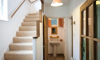 Una escalera que lleva a un baño con un lavamanos y una ventana encima.