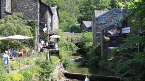 A stone building with a sign for 'The Gripping Goose Cafe' and 'Antlerhead Sheepskins'. - Acorn Cottage (Ambleside)