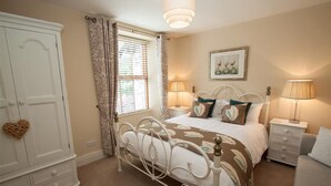 A bedroom with a bed, bedside tables, a wardrobe, and a window with curtains. - Acorn Cottage (Ambleside)