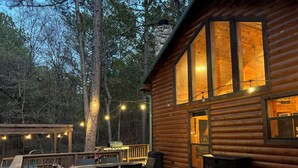 A wooden cabin with a deck, outdoor seating, and string lights. - Cozy cabin located in Beavers Bend, close to Broken Bow lake, Casino (Broken Bow)