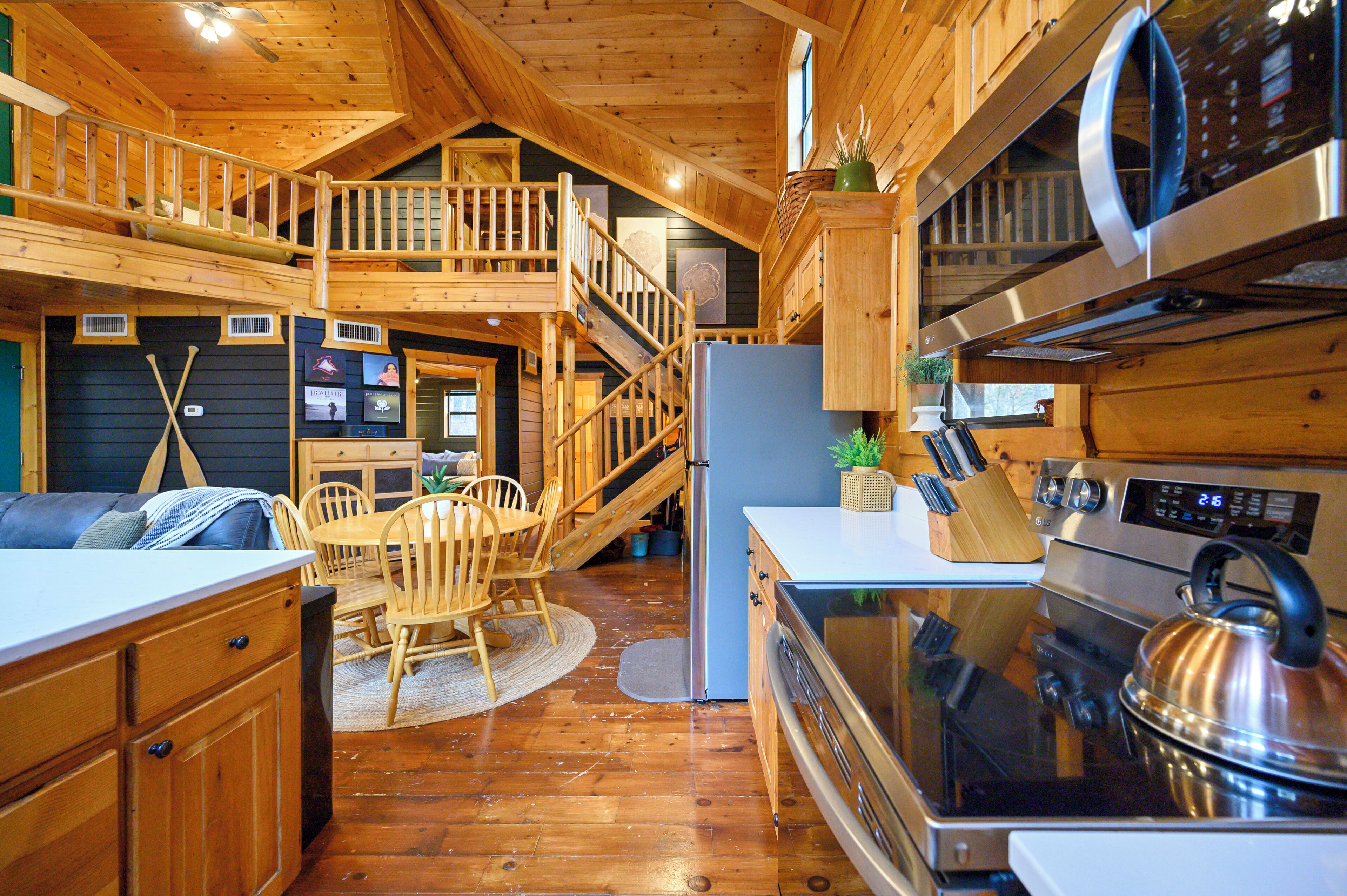 Interior de una cabaña de madera con cocina, comedor y habitación en altillo.