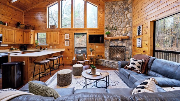 A cozy cabin interior with a stone fireplace, wooden walls, a bar area, and a comfortable seating space. - Cozy cabin located in Beavers Bend, close to Broken Bow lake, Casino (Broken Bow)