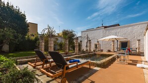 A courtyard with two lounge chairs, a small pool, and a white building with stone pillars. - 2320 Villa Ilse by Perle di Puglia (Andrano)