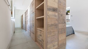A hallway with a wooden wardrobe and a bed with a blue bedspread. - 2320 Villa Ilse by Perle di Puglia (Andrano)