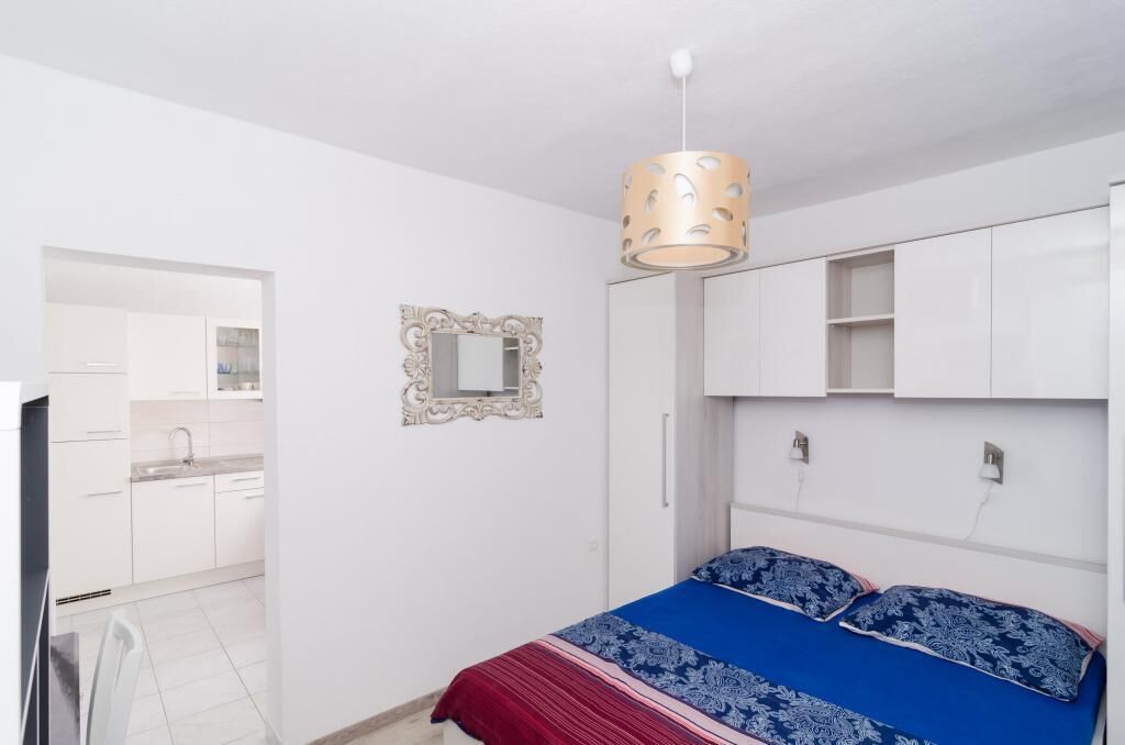 Une chambre à coucher avec un lit, un miroir et un luminaire suspendu.