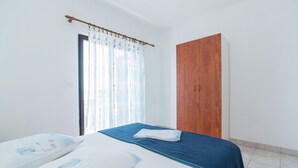 Ein Schlafzimmer mit Bett, einem Holzschrank und einem Fenster mit Vorhängen.